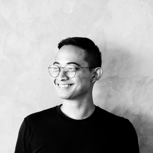 Arie standing in front of dense green foliage